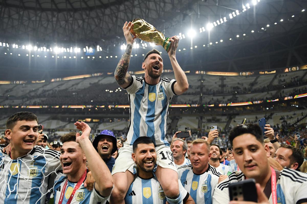 卡塔尔卢赛尔城 - 12 月 18 日：阿根廷队的莱昂内尔·梅西 (Lionel Messi) 在国际足联世界杯期间取得胜利后，在塞尔吉奥·“昆”·阿奎罗的肩上庆祝 2022 年卡塔尔世界杯冠军奖杯